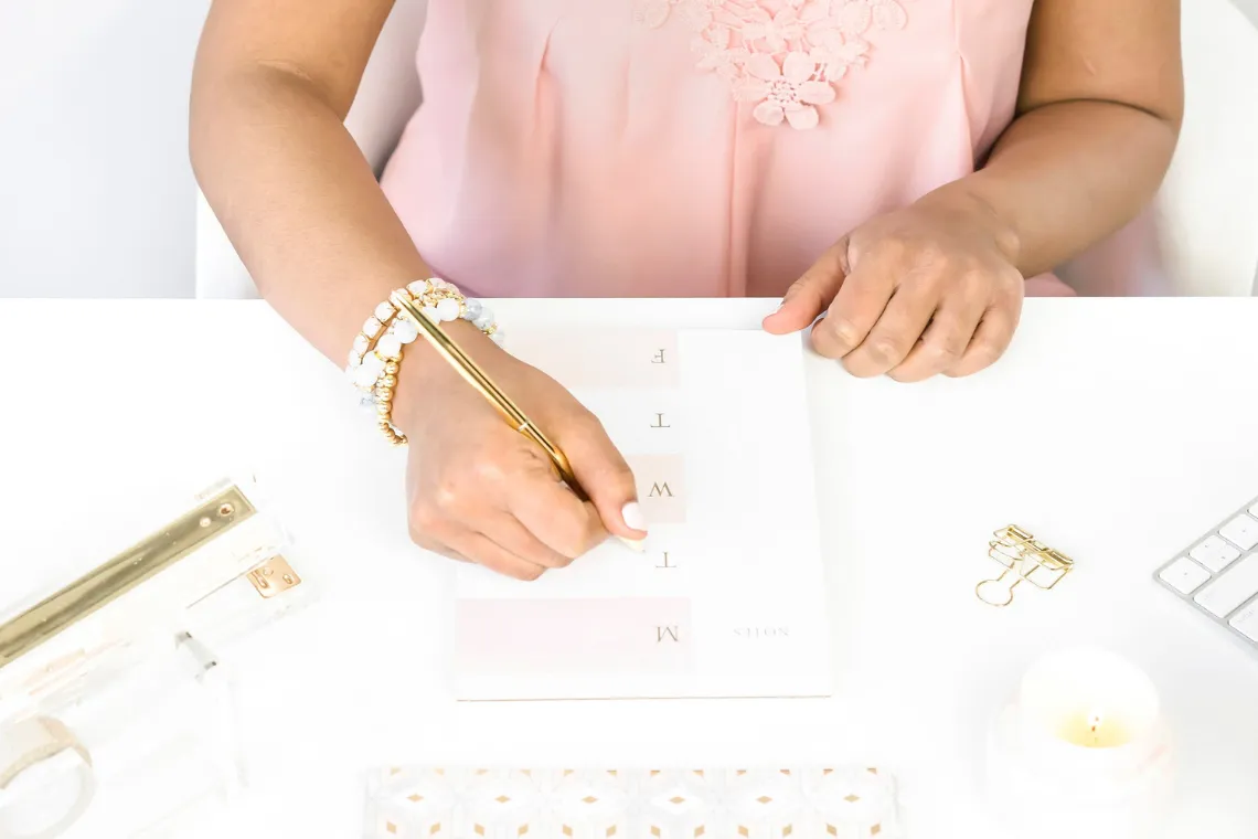A woman sitting at a desk, writing in her daily calendar.
