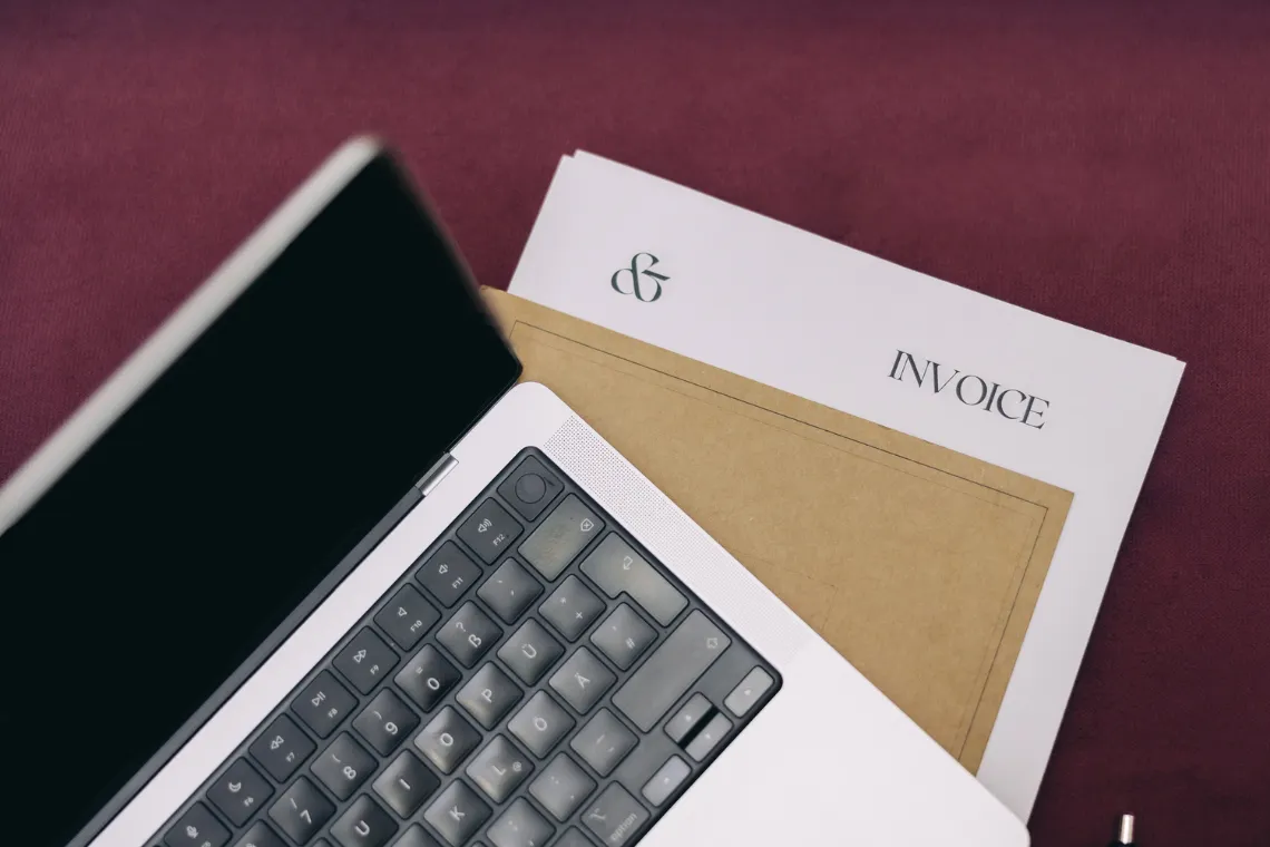 Open laptop on a table with notebooks and papers underneath.
