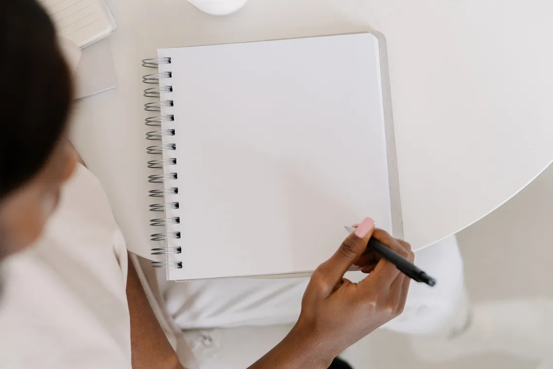 A woman writing in an open notebook.