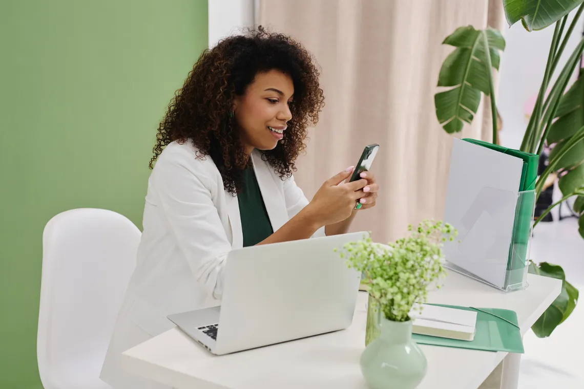 Businesswoman sitting at a desk with phone in hand, repurposing content.