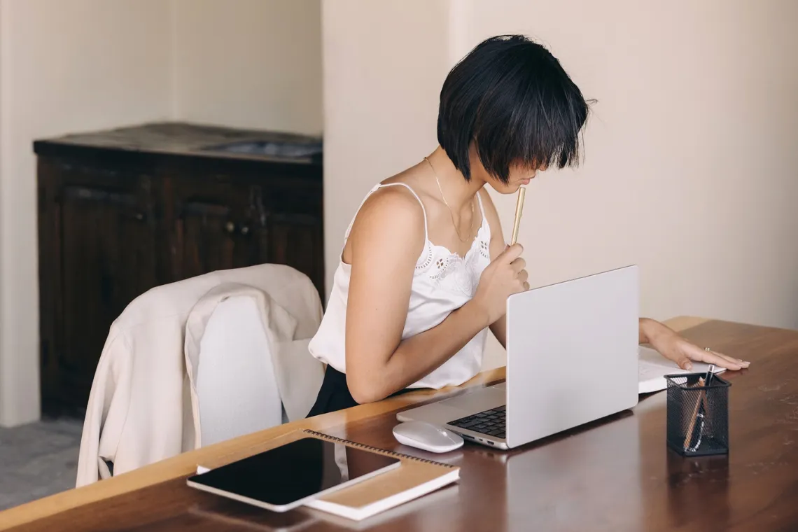 A woman sitting at a table with open laptop trying to optimise images for WordPress.
