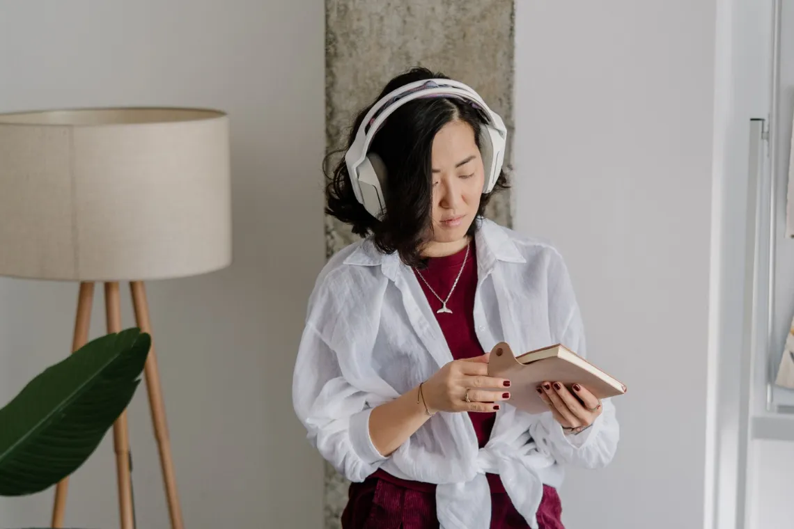 Woman with headphones holding a notebook in her hands.