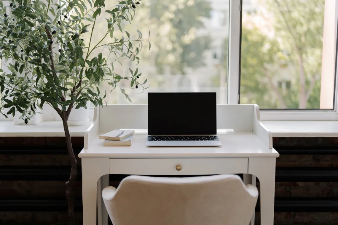 Desk with an open laptop and two notebooks with a pen.