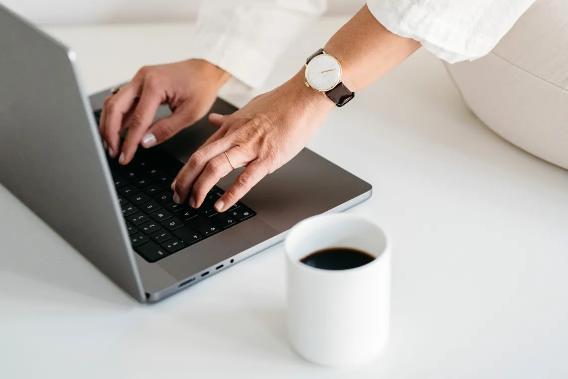 Woman typing on a laptop, designing a sustainable marketing strategy.