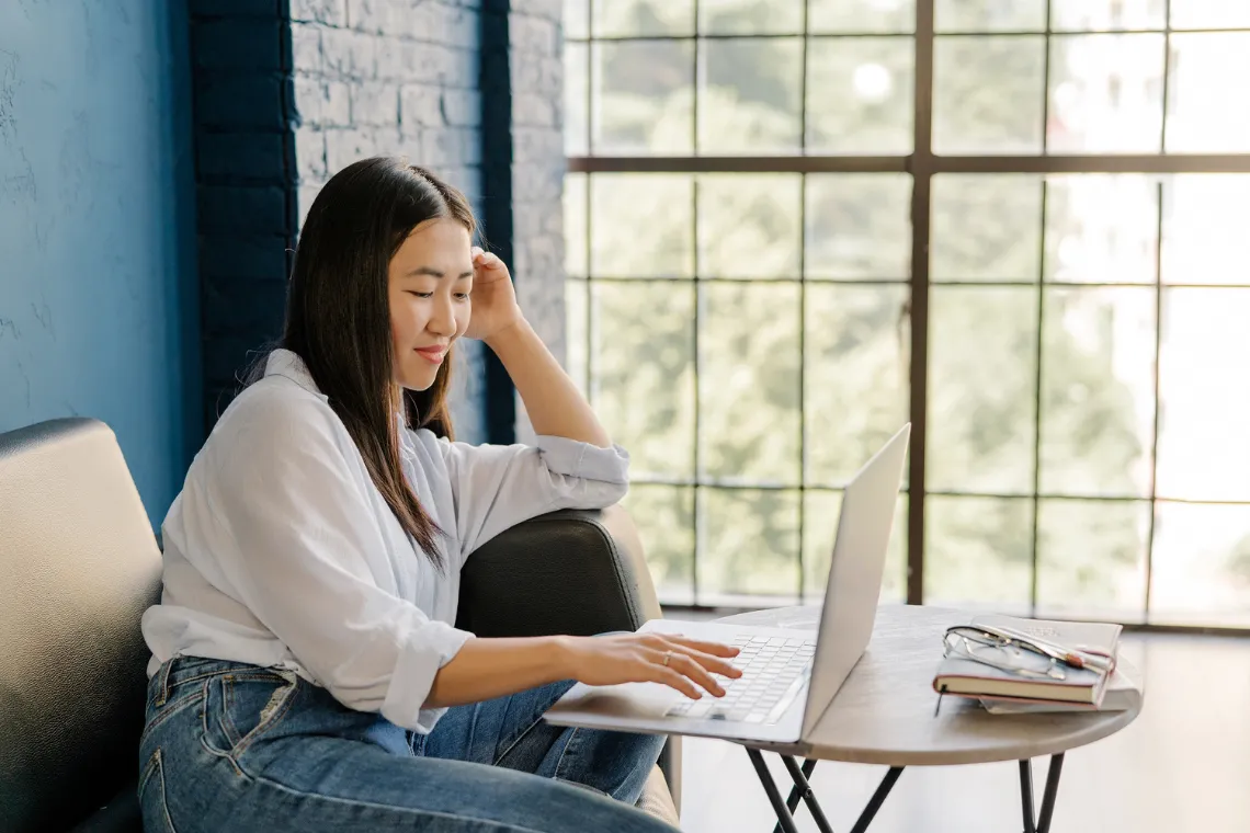 Businesswoman working on laptop at coffee table in a relaxed space.